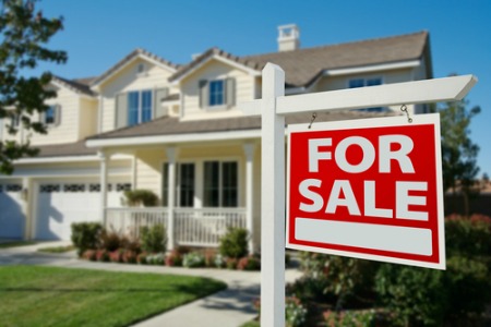 house in background with for sale sign in front