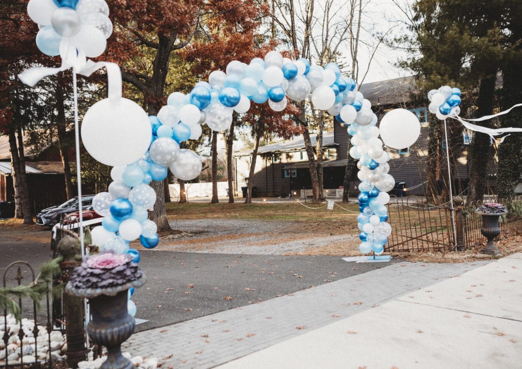 Blue and white balloon arch over drive to parking lot